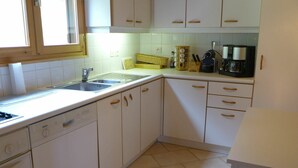 Una cocina con armarios blancos, lavavajillas Bosch, un lavaplatos y una cafetera.