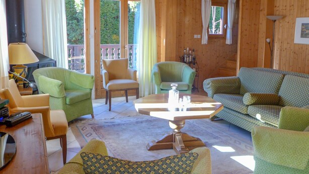 Un interior de madera acogedor con un sofá, sillas, una mesa de centro y un televisor.