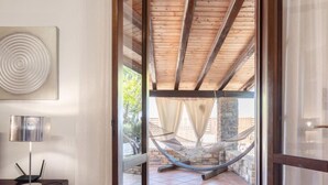 A doorway leading to a covered outdoor area with a hammock, a tiled floor, and a stone wall. - Nicole con Dependance by Interhome (Castellammare del Golfo)