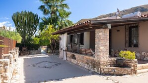 A house with a stone exterior, a patio with a stone table, and a large cactus in the background. - Nicole con Dependance by Interhome (Castellammare del Golfo)