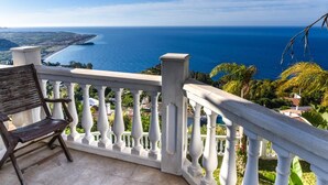 A balcony with a wooden chair, white balustrade, and a view of the sea and coastline. - Villa with pool located in the south of Spain (Salobreña)