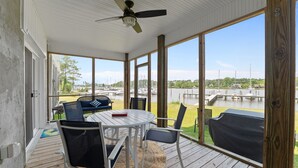 A covered outdoor area with a table and chairs, a ceiling fan, and a view of a marina with boats. - Waterfront Views & Boat Slip, Blackwell Point #C (Oriental)