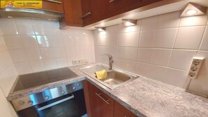 A compact kitchen with a stainless steel stove, an oven, a sink, and a granite countertop.