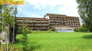 A multi-story building with a modern design, featuring balconies and solar panels.
