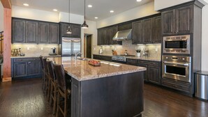 Una cocina moderna con armarios de madera oscura, electrodomésticos de acero inoxidable y una isla de granito.