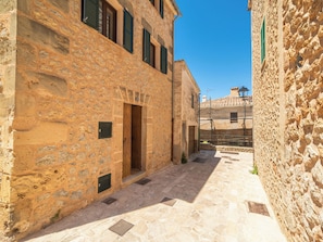 A narrow stone alleyway with a building on the left and a wall on the right.
