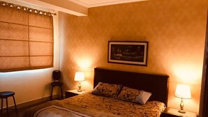 Une chambre à coucher avec un lit, deux tables de chevet, une chaise et une fenêtre avec des rideaux.