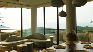 Una sala de estar moderna con un sofá, mesas redondas de centro y vistas al mar.