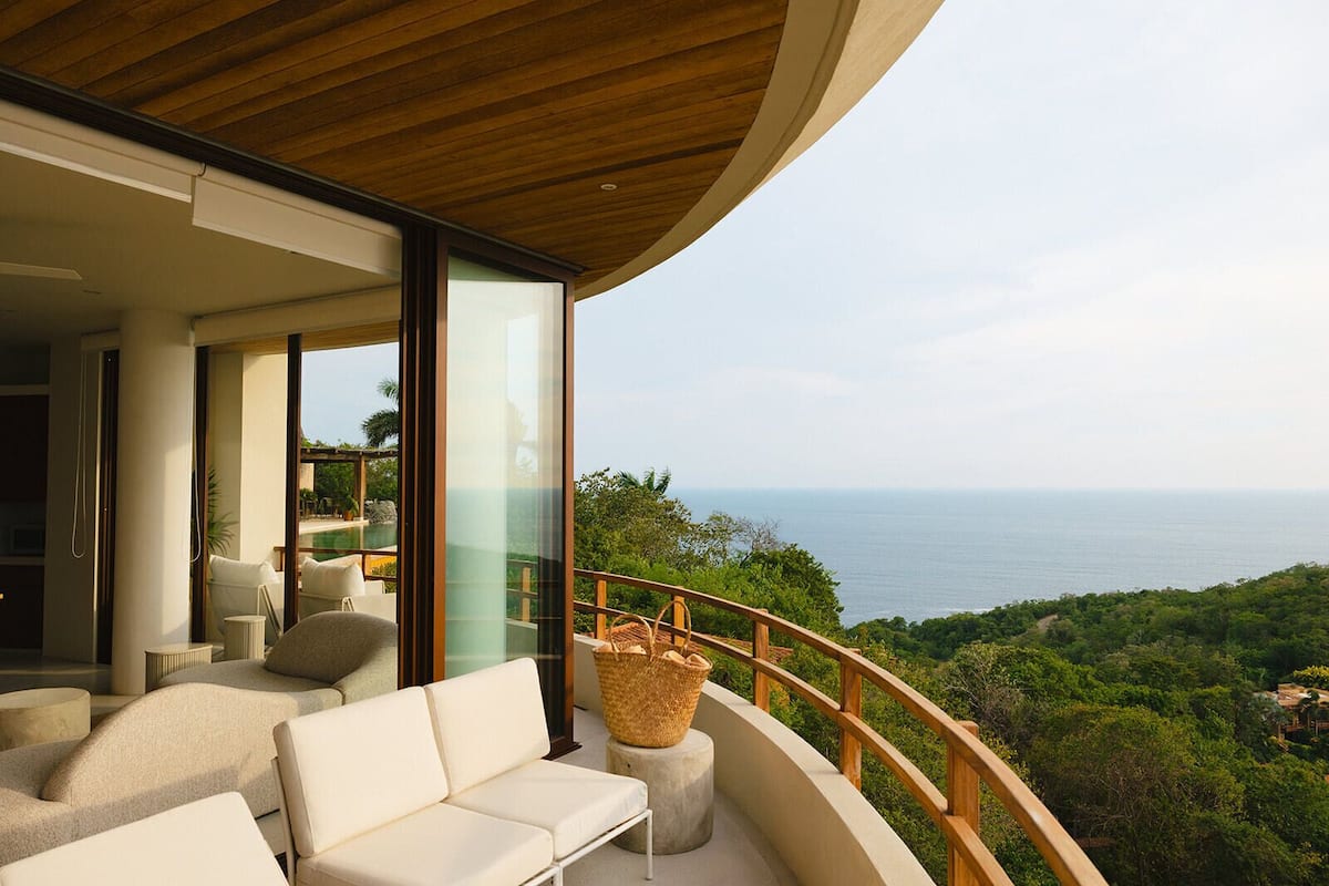 A modern outdoor seating area with a view of the ocean and lush greenery.
