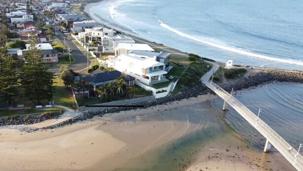 An aerial view of a coastal residential area with houses, a beach, and a bridge. - 'LITTLE LAKE LODGE' - on Warilla Beach / Little Lake (Warilla)