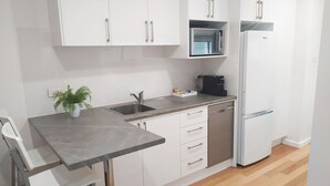 A modern kitchen with white cabinets, a stainless steel sink, a coffee maker, and a built-in microwave. - 'LITTLE LAKE LODGE' - on Warilla Beach / Little Lake (Warilla)