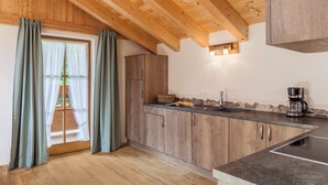 Eine Küche mit Holzausstattung, einer Arbeitsplatte, einer Kaffeemaschine und einem Fenster mit Vorhängen.
