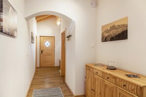 A hallway with wooden flooring, a wooden cabinet, and a door at the end.