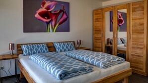 Une chambre à coucher comprenant un lit, une armoire en bois, des tables de chevet et un tableau accroché au mur.