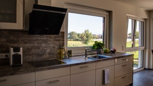 Une cuisine moderne dotée d’un four encastré, d’une grande fenêtre et offrant une vue sur l’extérieur.