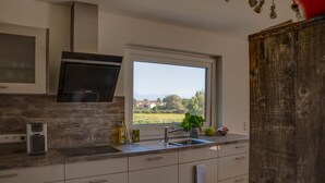A modern kitchen with a large window, built-in oven, and a rustic wooden cabinet.