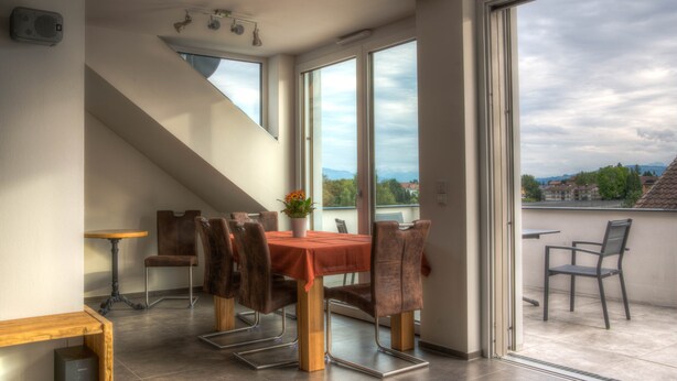 A dining area with a table and chairs, a small table, and a speaker.