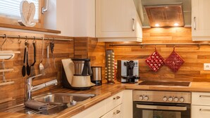A modern kitchen with wooden cabinetry, stainless steel appliances, and a coffee maker. - Vacation Home "Das Bergzeit" with Mountain View, Wi-Fi, Garden & Terrace (Farchant)