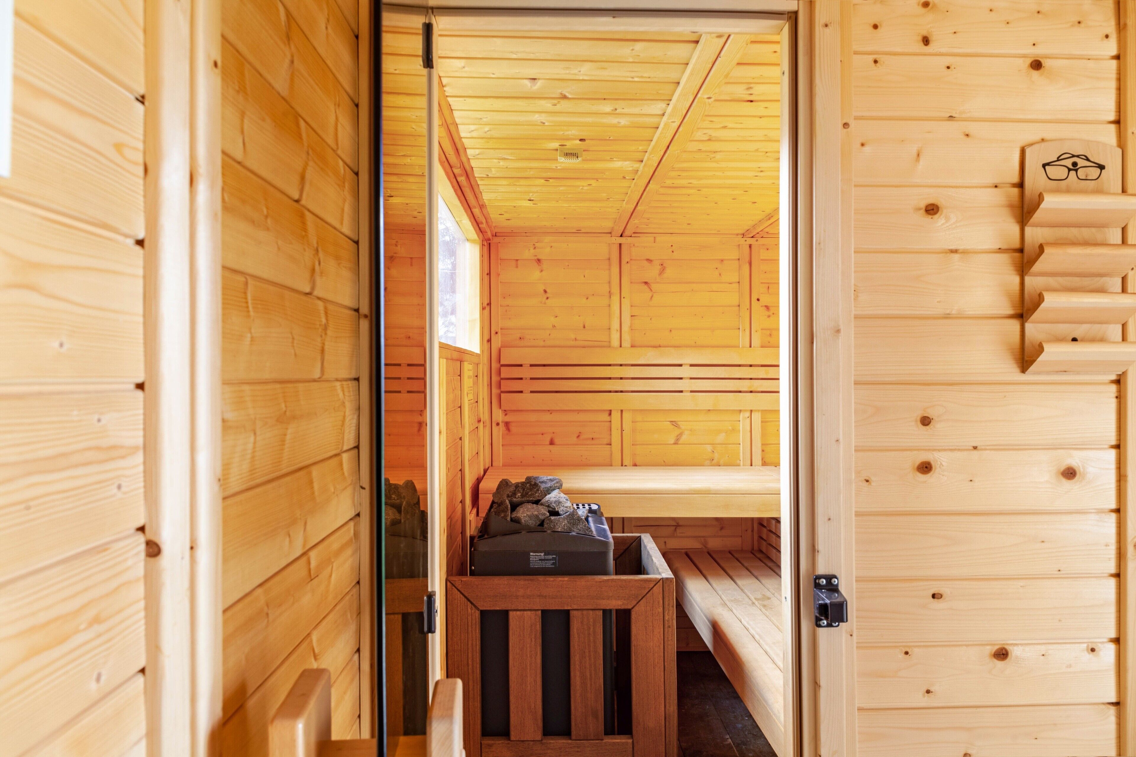 Un intérieur en bois avec un banc, une petite table ornée de pierres et une étagère avec des verres.