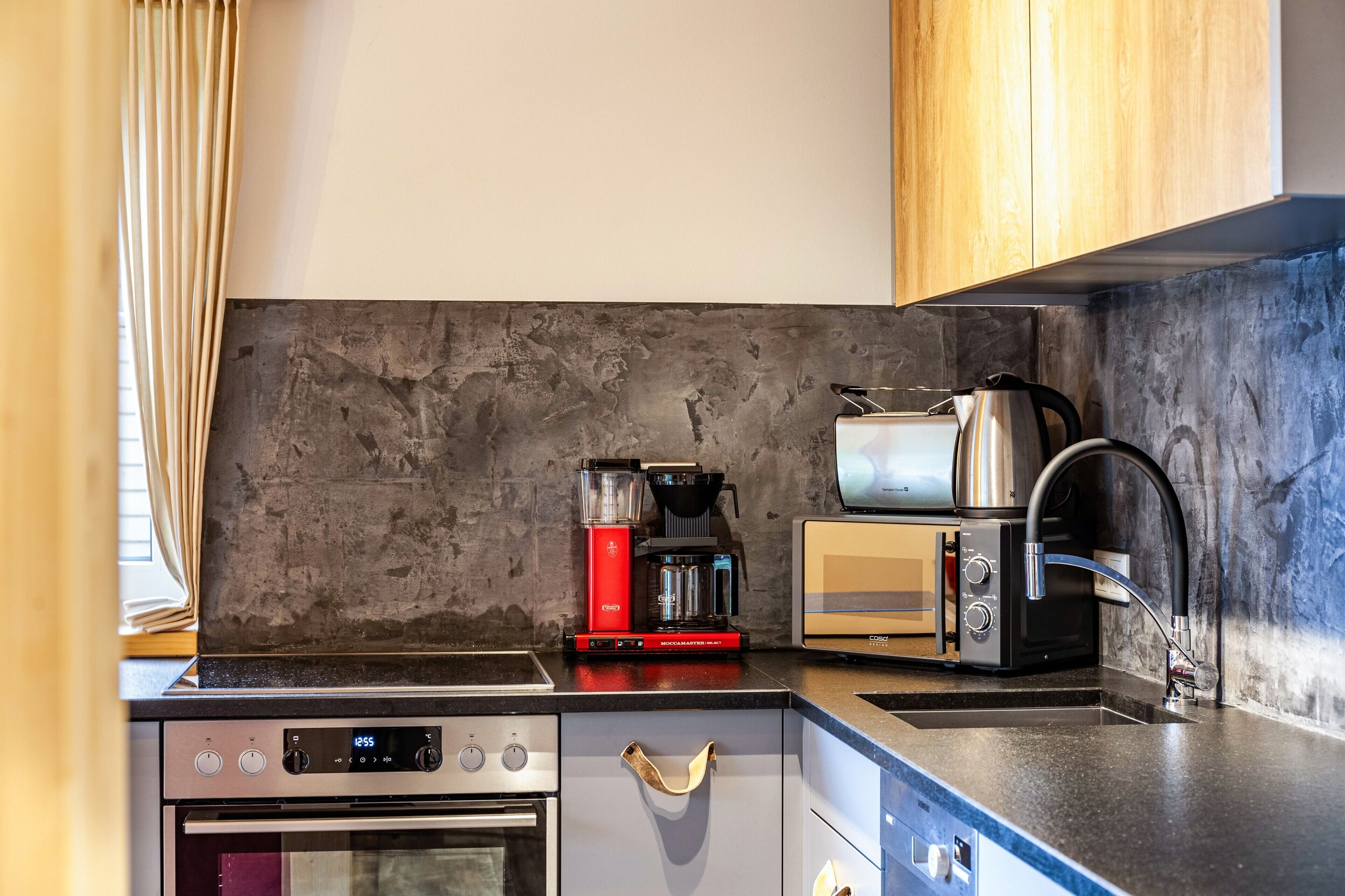 A kitchen with a modern design, including a coffee maker, toaster, and oven.