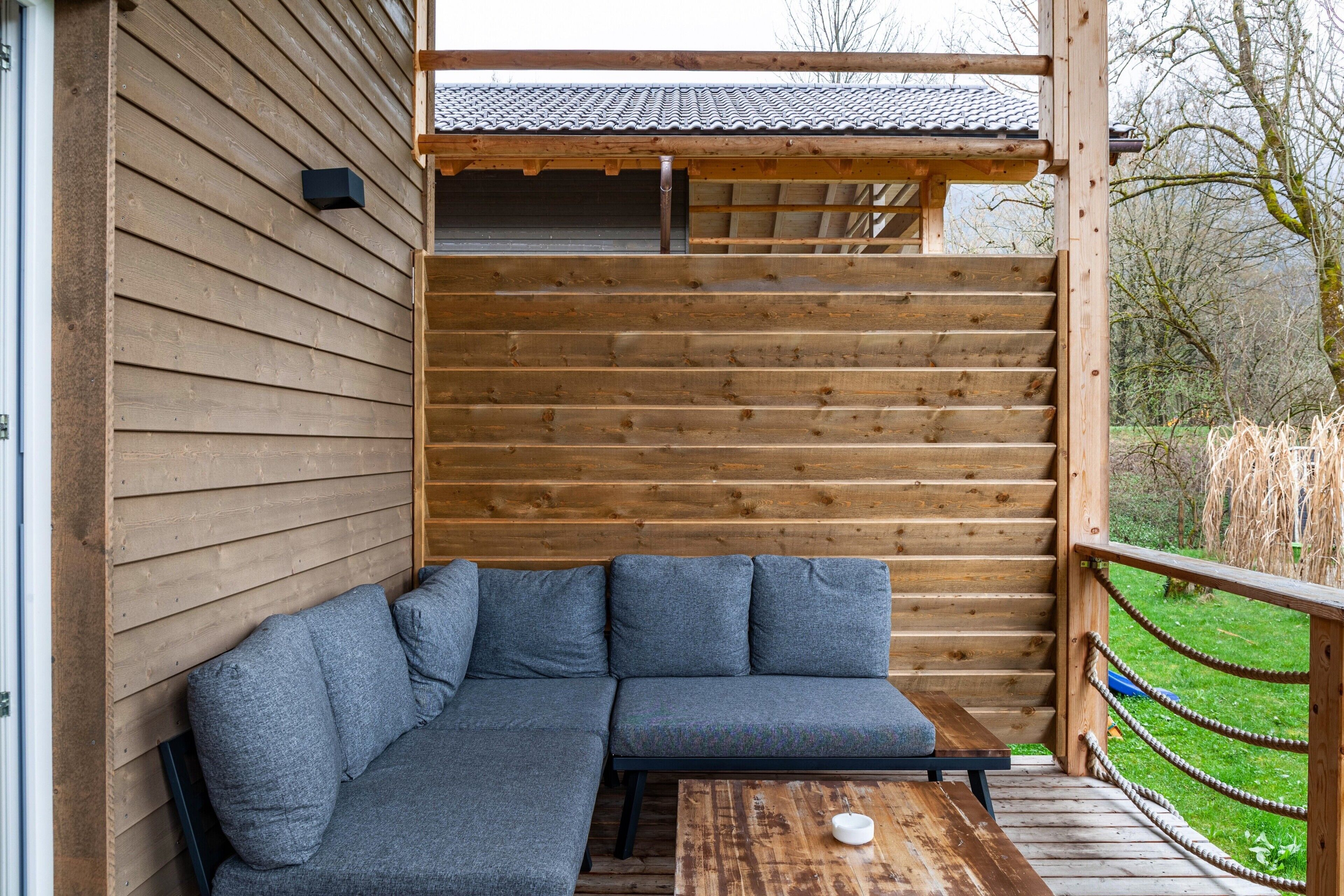 Une terrasse en bois avec un canapé intégré et une petite table.