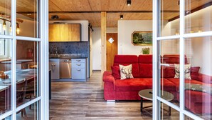 A modern interior with a wooden ceiling, a red sofa, a dining area, and a kitchen. - Chalet Rauschn with mountain view with shared sauna, terrace, balcony; pet friendly (Farchant)