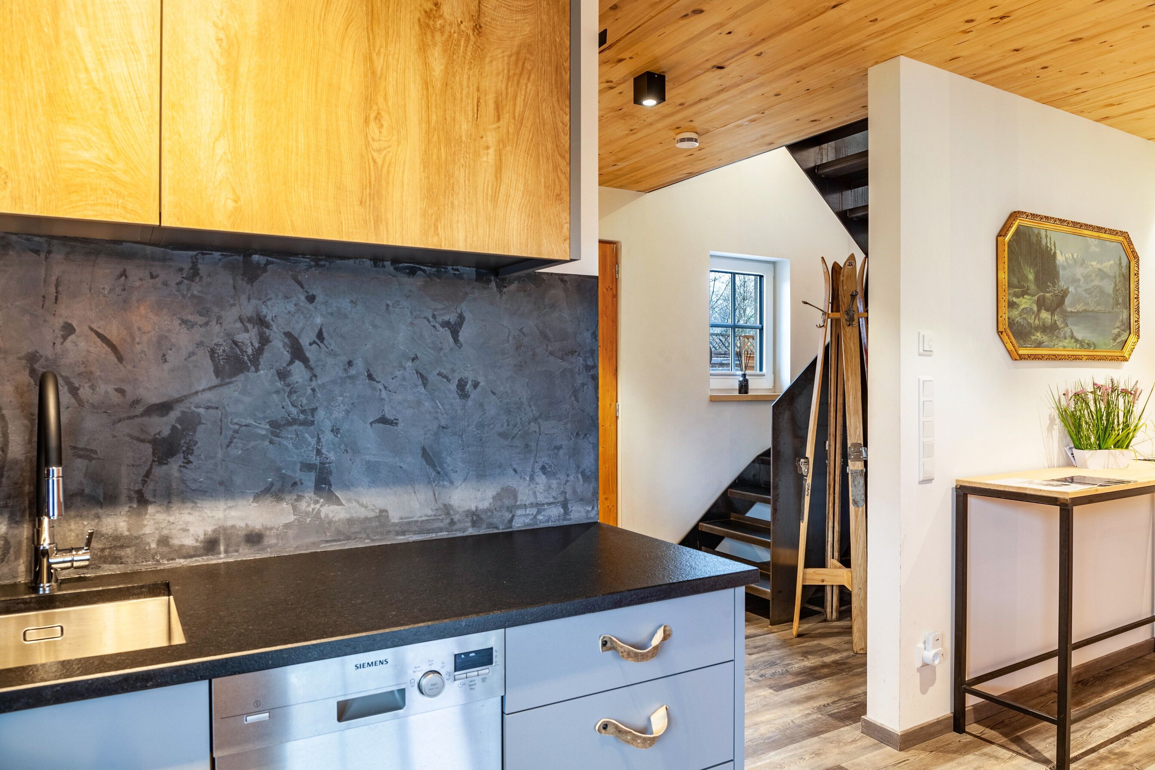A modern kitchen with a stainless steel dishwasher, wooden cabinets, and a stone backsplash.