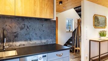A modern kitchen with a stainless steel dishwasher, wooden cabinets, and a stone backsplash.