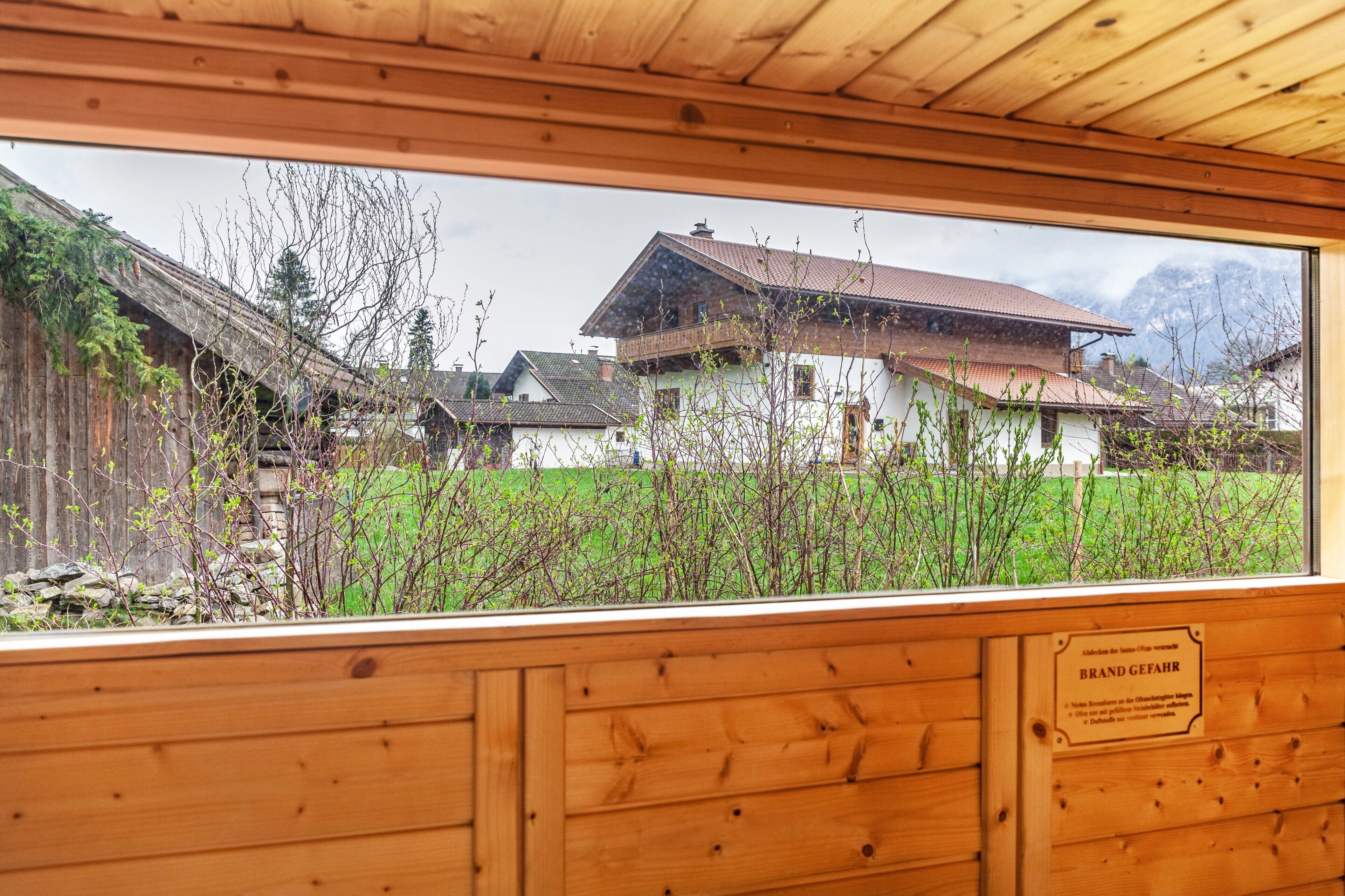 Een houten interieur met uitzicht op traditionele huizen en een stenen muur.