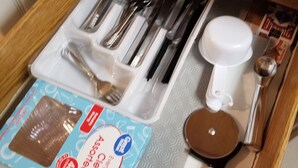 A drawer containing various kitchen utensils, including a whisk, spatula, and measuring spoons.