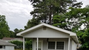 A small, single-story house with a porch and a fenced yard.
