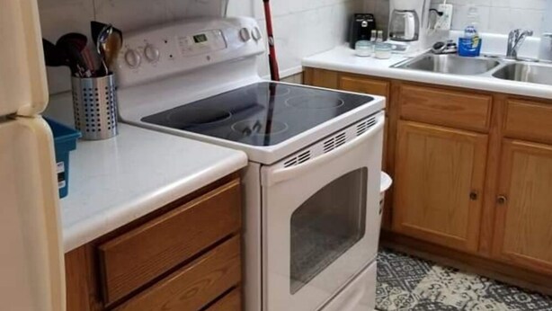 A kitchen with wooden cabinets, a white microwave, a stove, and a coffee maker.