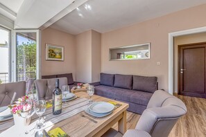 Un comedor con una mesa preparada para dos personas, un sofá y una puerta.