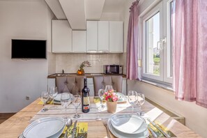 Un comedor con una mesa dispuesta para dos personas, una botella de vino y un ramo de flores.