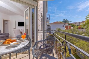 Ein Balkon mit Esstisch, Stühlen und Fernseher.