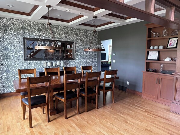 A dining area with a wooden table and chairs, a patterned wallpaper, and a ceiling with exposed beams. - Quiet Home away from Home (Oshkosh)