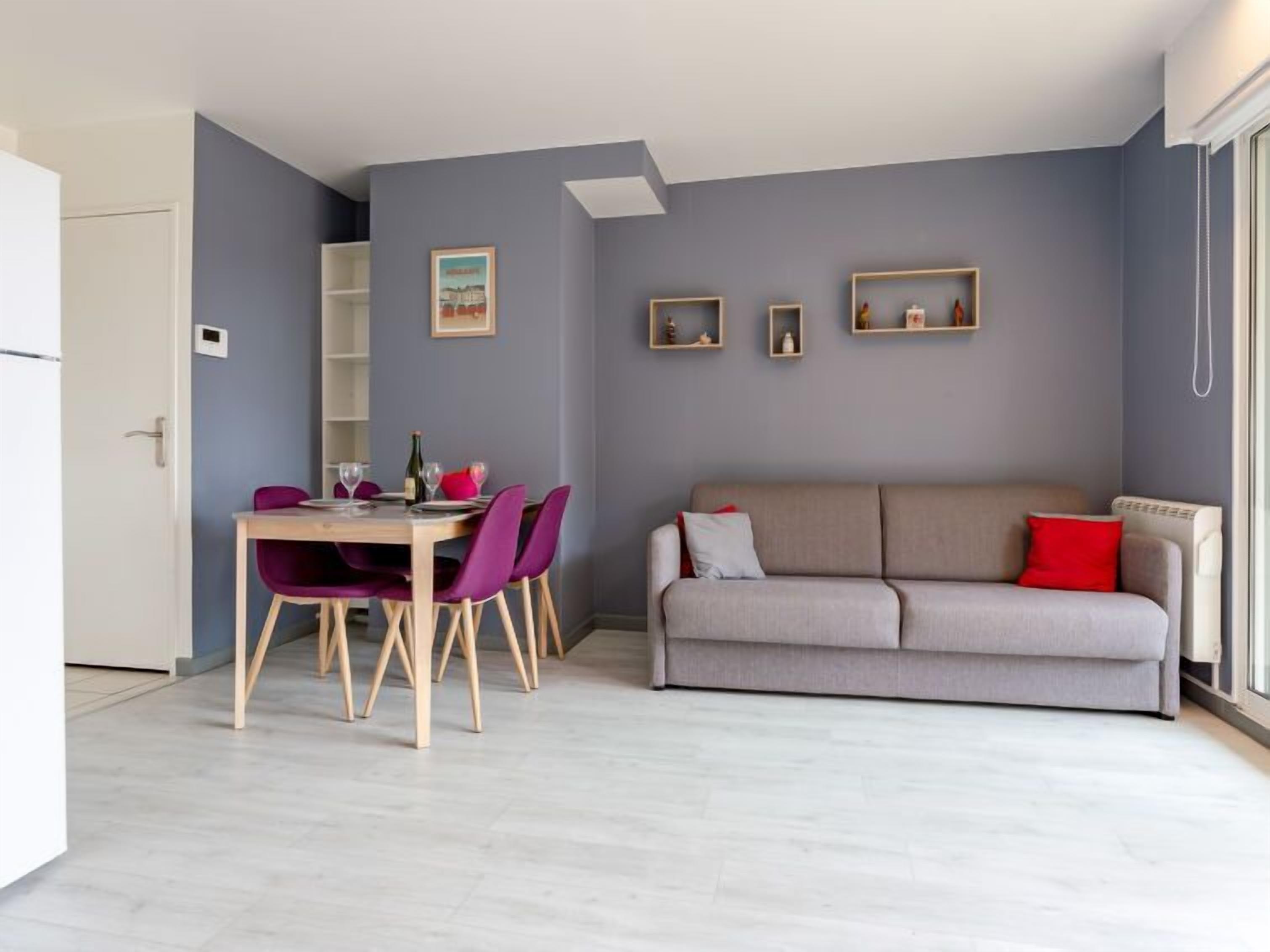 A compact living space with a dining area, a sofa, and a small kitchen.