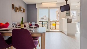 Ein moderner Essbereich mit einem Tisch für zwei Personen, einer Weinflasche und einem an der Wand montierten Fernseher.