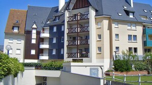 Ein mehrgeschossiges Wohngebäude mit Balkonen, einer flachen Dachkonstruktion und einer Mischung verschiedener Baustile.