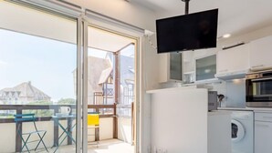 Eine moderne Küche mit Einbauwaschmaschine, Flachbildfernseher und einem Balkon mit Blick auf Häuser.