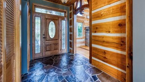 A wooden interior with a stone-tiled floor and a large wooden door with glass panels. - Large Grand Bend Getaway. Swim, Golf, Relax (South Huron (Munic))