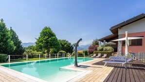 Una piscina con muelle de madera, rodeada de vegetación y vistas a la montaña.