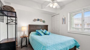 A bedroom with a bed, a nightstand, a wardrobe, a ceiling fan, a window with blinds, and a wall-mounted artwork. - Welcome to PARADISE POINTE, your ultimate oceanfront retreat in North Myrtle Beach (North Myrtle Beach)