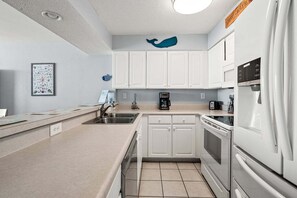 Een moderne keuken met witte kasten, een roestvrijstalen spoelbak en een koelkast.