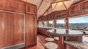 A kitchen with wooden cabinets, a granite countertop, and a view of mountains. - Escape to “Casa Paradiso” in the Napa Valley! (Calistoga)