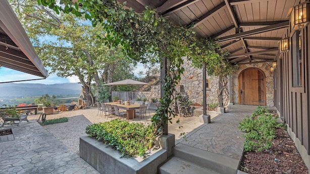 An outdoor patio with stone flooring, a wooden pergola, and a stone wall. - Escape to “Casa Paradiso” in the Napa Valley! (Calistoga)