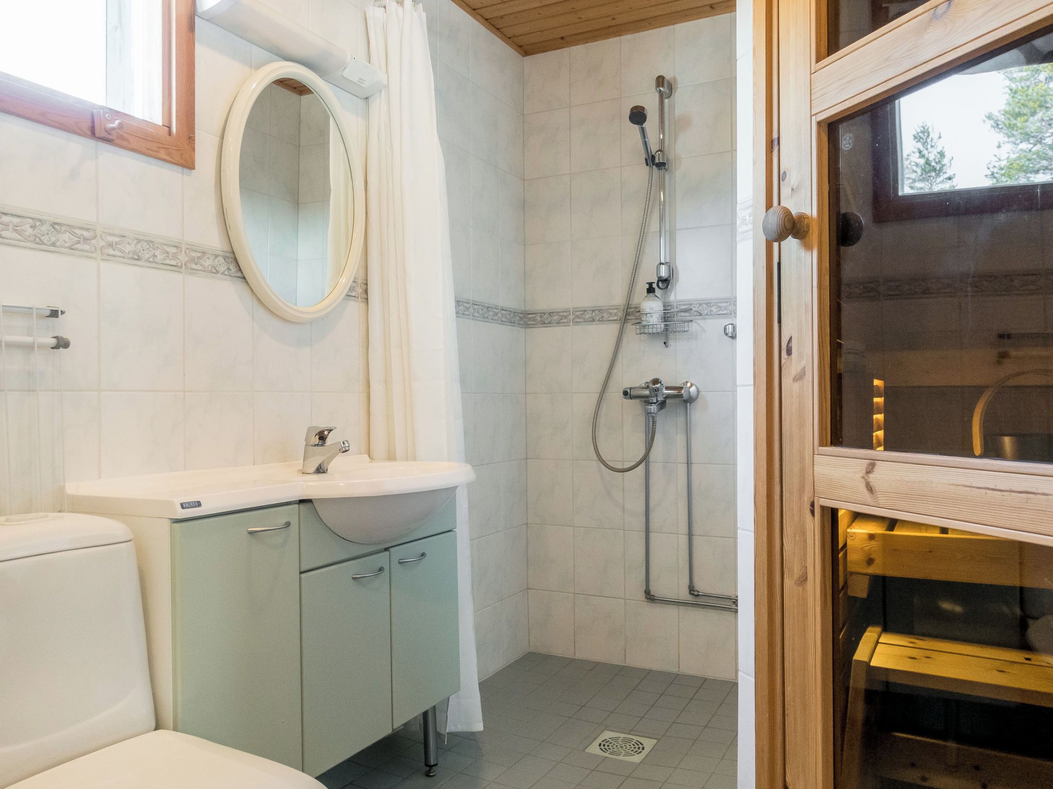 Une salle de bain équipée de toilettes, d’un lavabo, d’un miroir, d’une douche et d’une porte en bois.