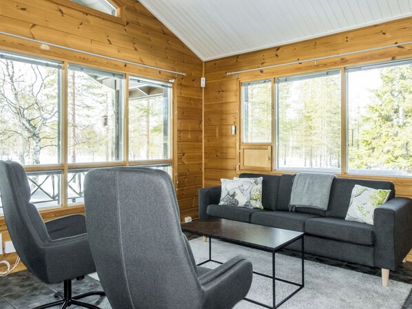 A room with a wooden interior, a sofa, a chair, and a coffee table.
