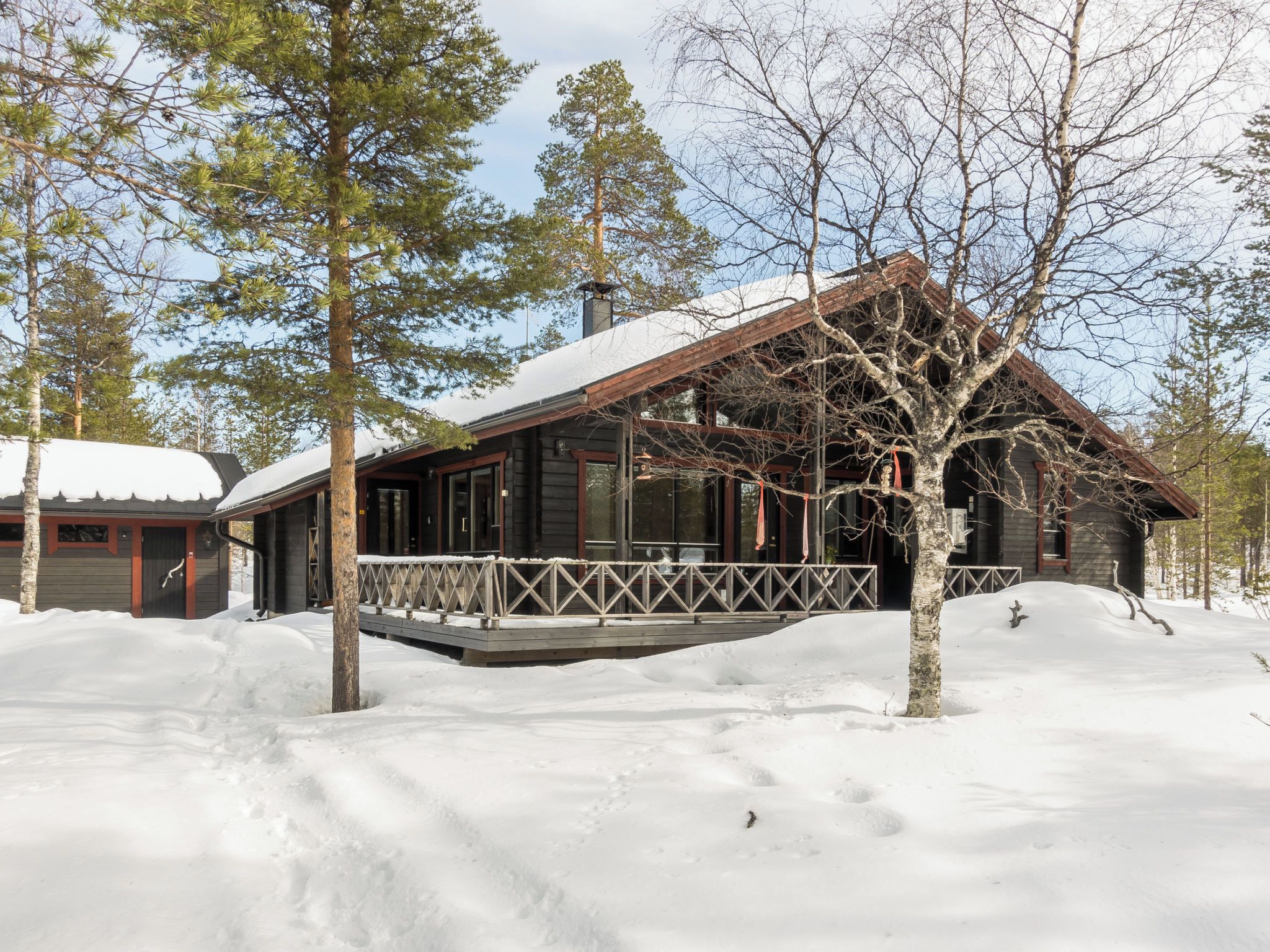 Une cabane avec une façade en bois, une véranda et un toit recouvert de neige.