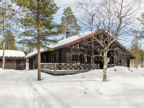 A cabin with a wooden exterior, a porch, and a snow-covered roof.
